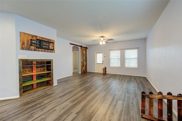 living room with ceiling fan, wood-type flooring, and a barn door