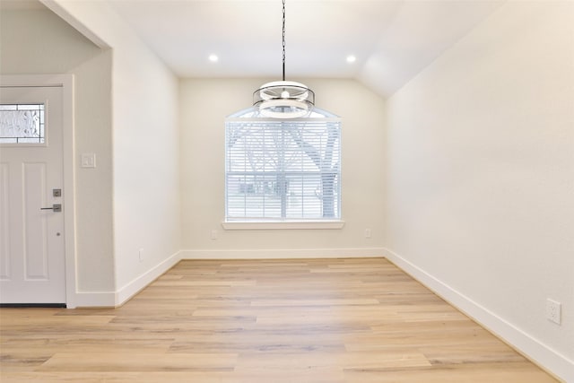 unfurnished dining area featuring vaulted ceiling and light hardwood / wood-style floors