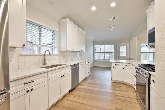 kitchen with sink, white cabinets, backsplash, light hardwood / wood-style floors, and stainless steel appliances