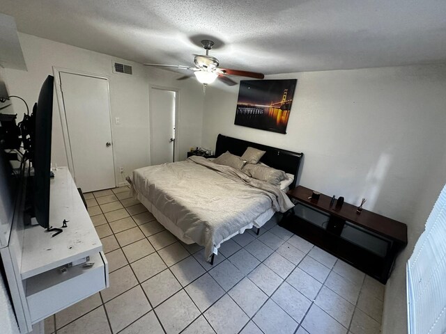 bedroom with a textured ceiling, a closet, light tile patterned floors, and ceiling fan