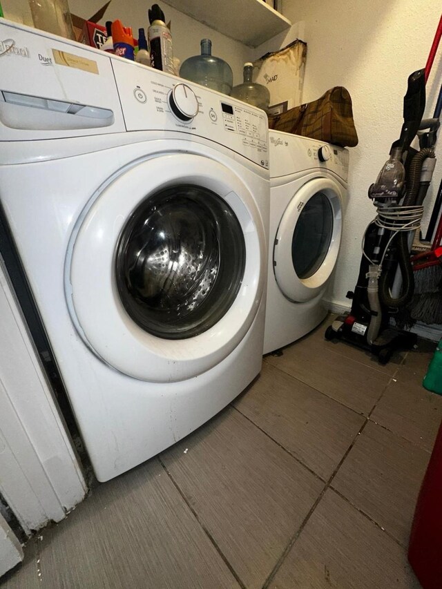 laundry room featuring washer and clothes dryer and dark tile patterned flooring