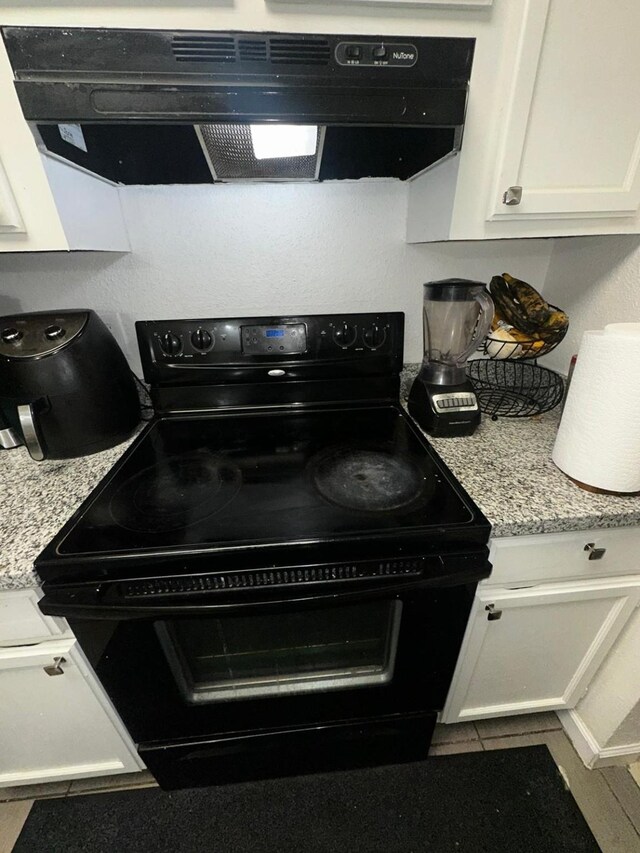 kitchen with white cabinetry, range hood, light stone countertops, and black range with electric cooktop