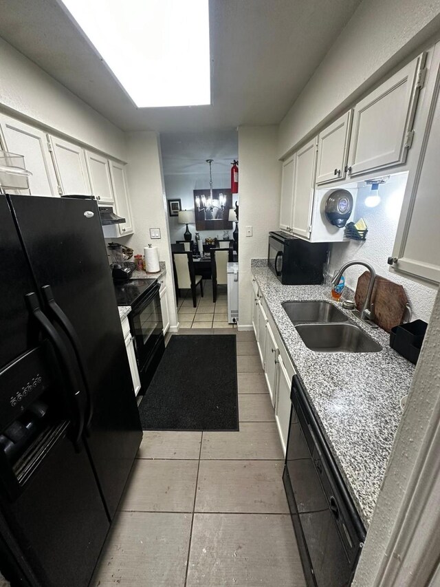 kitchen featuring sink, black appliances, white cabinetry, and light stone counters