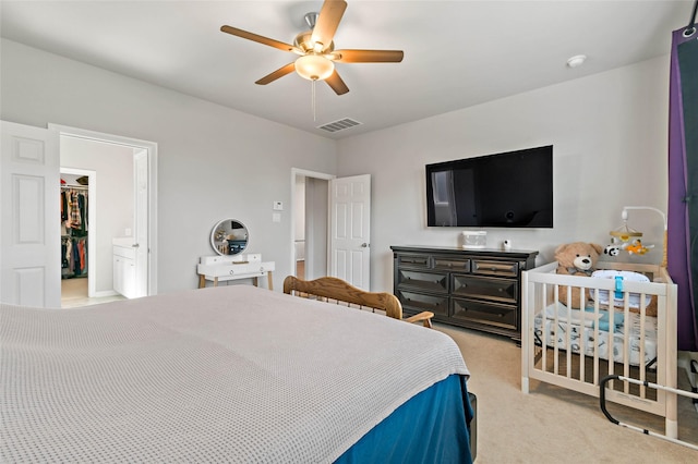 bedroom featuring a spacious closet, a closet, light carpet, and ceiling fan