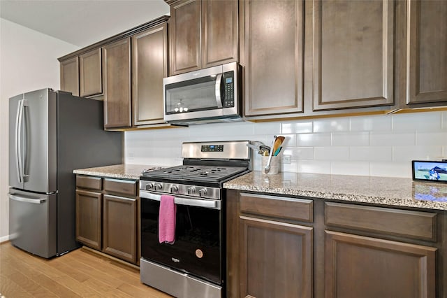 kitchen featuring tasteful backsplash, stainless steel appliances, light stone countertops, light hardwood / wood-style floors, and dark brown cabinetry