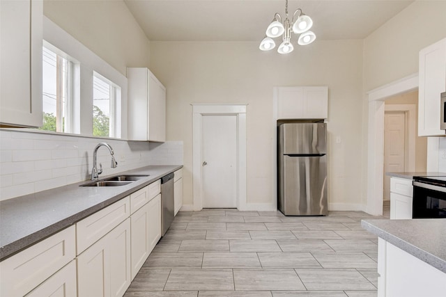 kitchen featuring white cabinetry, stainless steel appliances, sink, backsplash, and hanging light fixtures