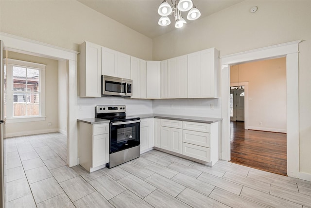 kitchen with white cabinetry, an inviting chandelier, appliances with stainless steel finishes, and decorative backsplash