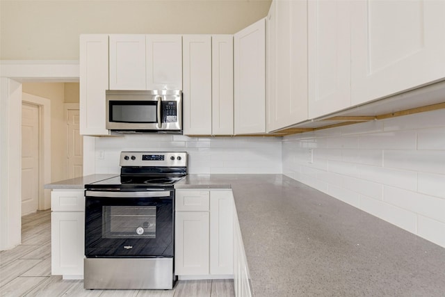 kitchen with backsplash, white cabinetry, and appliances with stainless steel finishes