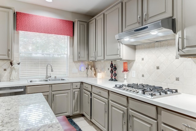 kitchen featuring appliances with stainless steel finishes, light tile patterned floors, gray cabinetry, decorative backsplash, and sink