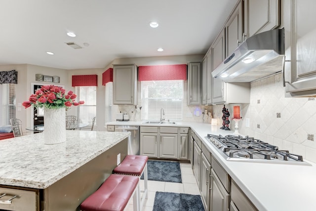 kitchen featuring a kitchen bar, sink, backsplash, stainless steel appliances, and light tile patterned flooring