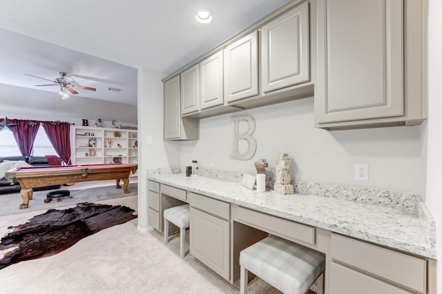 kitchen featuring light stone countertops, billiards, light carpet, built in desk, and ceiling fan