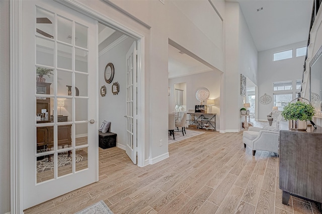 entryway featuring french doors, a towering ceiling, and light hardwood / wood-style floors