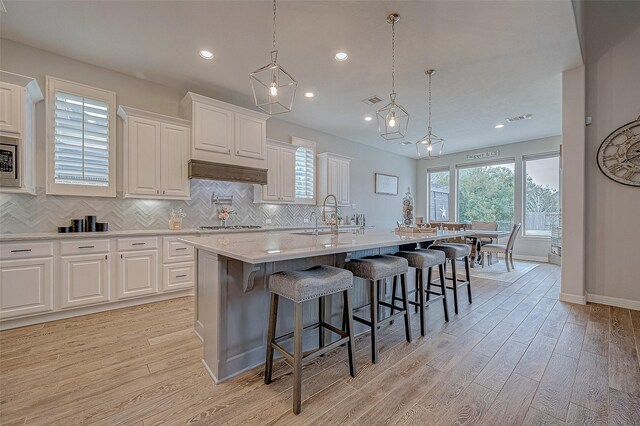 kitchen with a breakfast bar, a center island with sink, and white cabinets