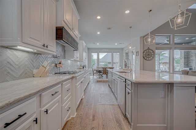 kitchen featuring stainless steel appliances, white cabinetry, an island with sink, and decorative backsplash