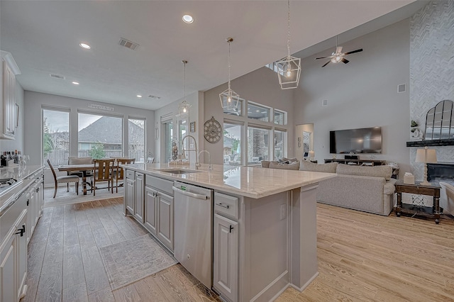 kitchen featuring sink, white cabinetry, light hardwood / wood-style floors, an island with sink, and stainless steel dishwasher