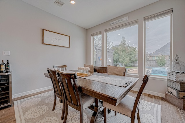 dining space with beverage cooler and light hardwood / wood-style floors