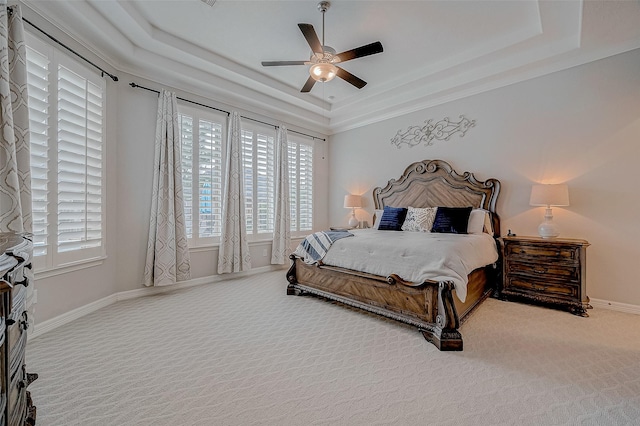 carpeted bedroom with a raised ceiling and ceiling fan