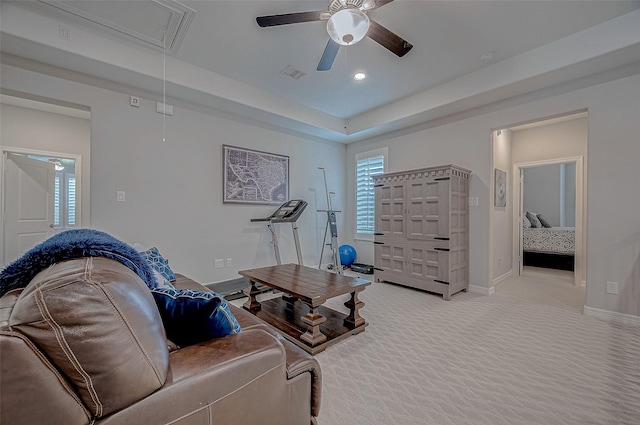 carpeted living room featuring a raised ceiling and ceiling fan