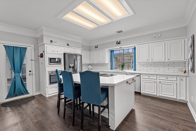 kitchen featuring stainless steel appliances, a center island, white cabinets, and a kitchen breakfast bar