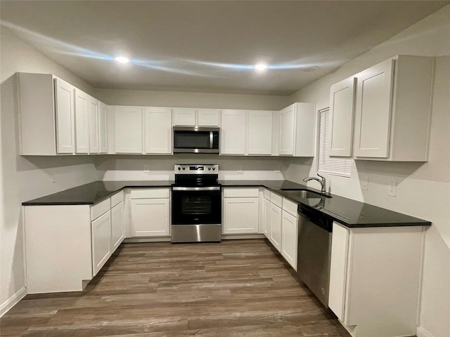 kitchen with sink, white cabinets, dark wood-type flooring, and appliances with stainless steel finishes