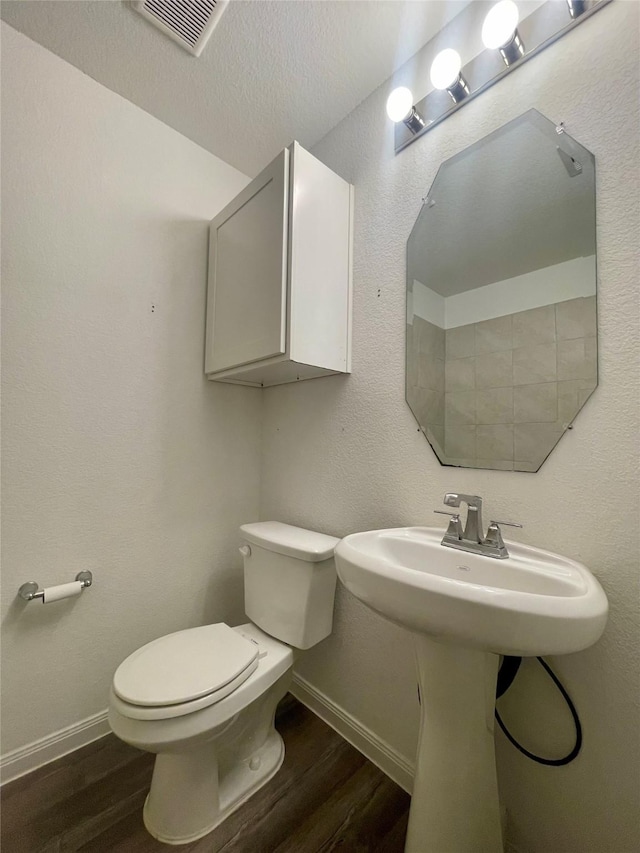 bathroom with wood-type flooring, a textured ceiling, and toilet