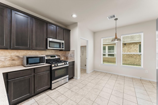 kitchen featuring hanging light fixtures, light tile patterned floors, dark brown cabinets, backsplash, and stainless steel appliances