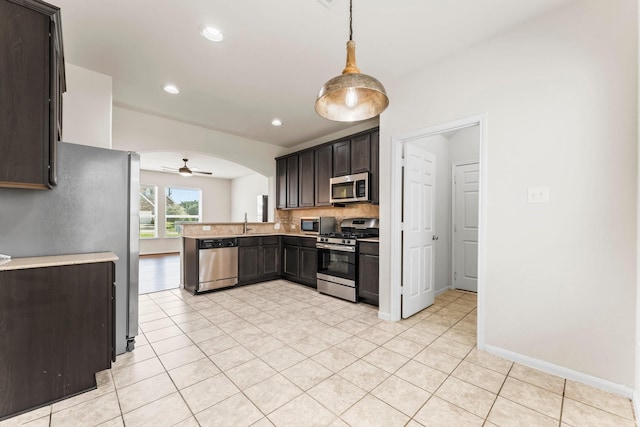 kitchen with appliances with stainless steel finishes, dark brown cabinets, decorative light fixtures, sink, and backsplash