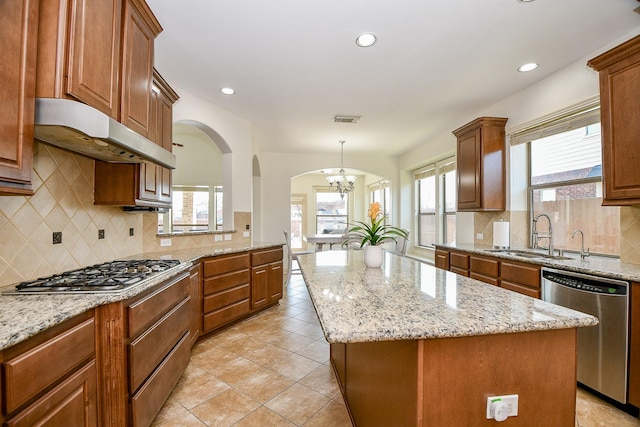 kitchen with stainless steel appliances, a center island, sink, and decorative light fixtures