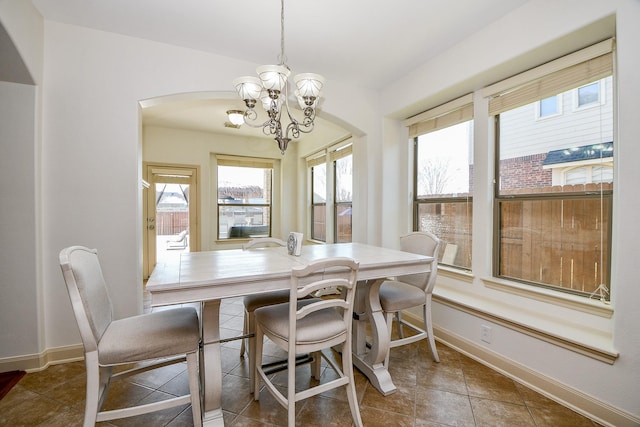 dining area featuring dark tile patterned floors and a notable chandelier