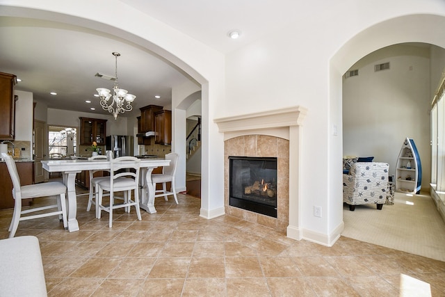 interior space featuring light tile patterned floors, a tile fireplace, and a notable chandelier