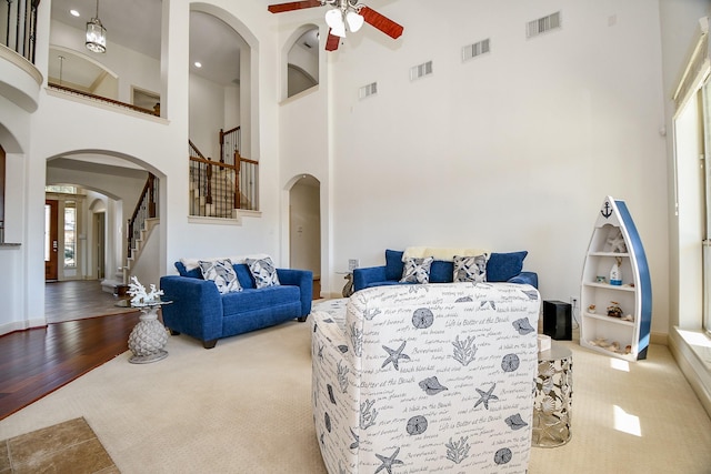 carpeted living room featuring ceiling fan, a towering ceiling, and built in features