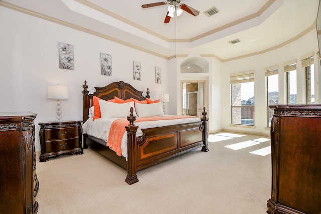 carpeted bedroom with ceiling fan, ornamental molding, and a tray ceiling