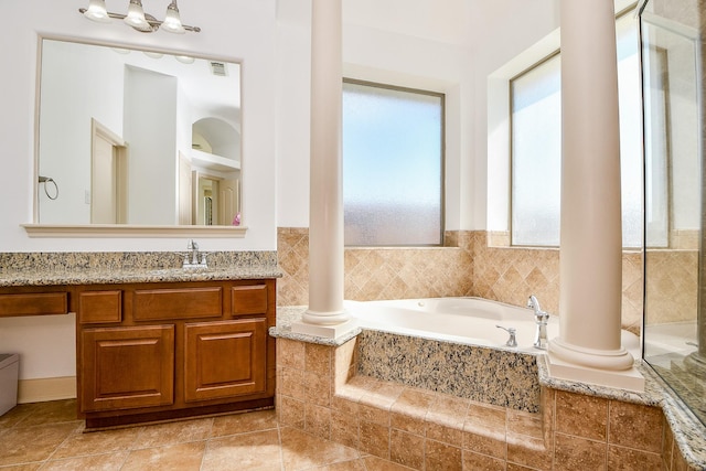 bathroom with a relaxing tiled tub, vanity, and ornate columns