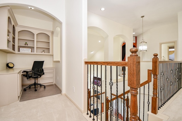 carpeted home office with an inviting chandelier, built in desk, and built in features