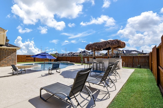 view of pool featuring an in ground hot tub, pool water feature, a patio area, and a bar