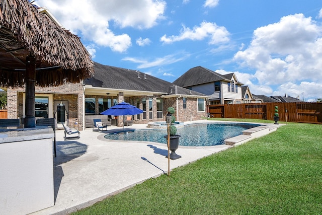 view of swimming pool featuring a lawn, a patio, and an in ground hot tub