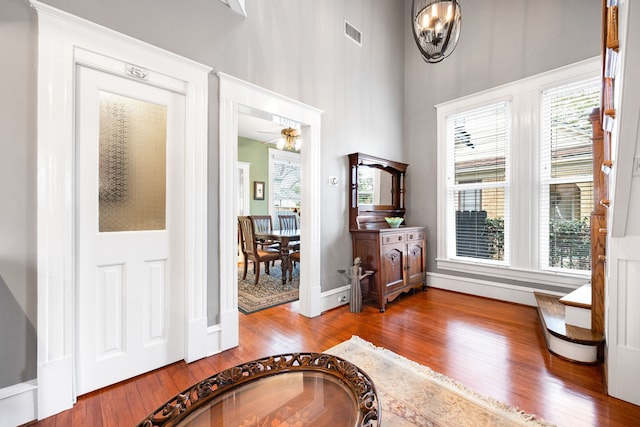 foyer featuring hardwood / wood-style floors, ceiling fan with notable chandelier, and a healthy amount of sunlight