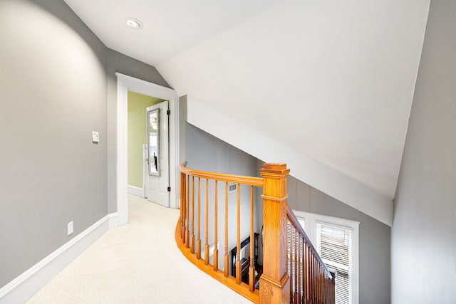 hallway featuring lofted ceiling and light carpet