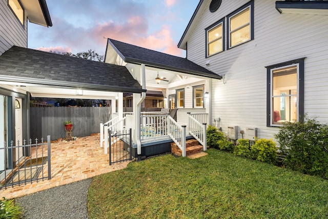 back house at dusk featuring a yard and ceiling fan