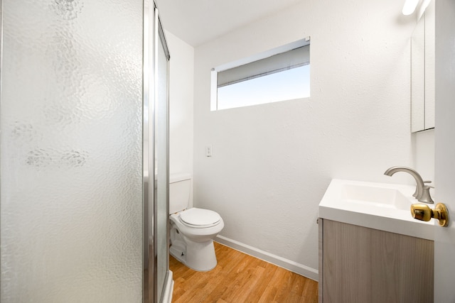 bathroom featuring hardwood / wood-style flooring, vanity, toilet, and a shower with shower door