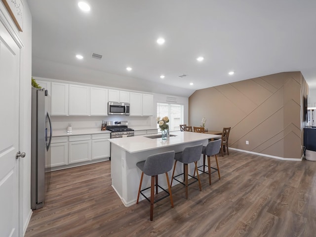 kitchen with white cabinets, a kitchen island with sink, dark wood-type flooring, and stainless steel appliances