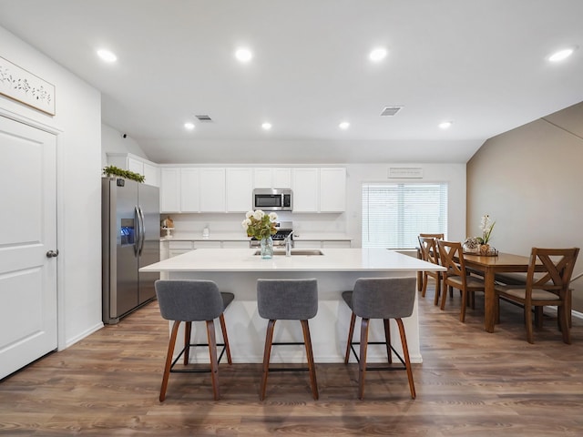 kitchen featuring white cabinets, a center island with sink, appliances with stainless steel finishes, and dark hardwood / wood-style flooring