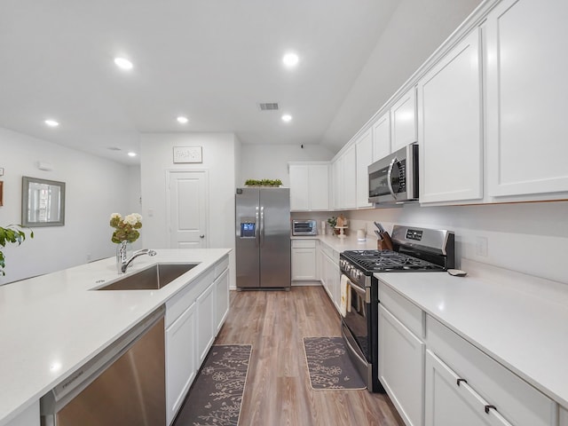 kitchen with light hardwood / wood-style floors, sink, white cabinets, and stainless steel appliances