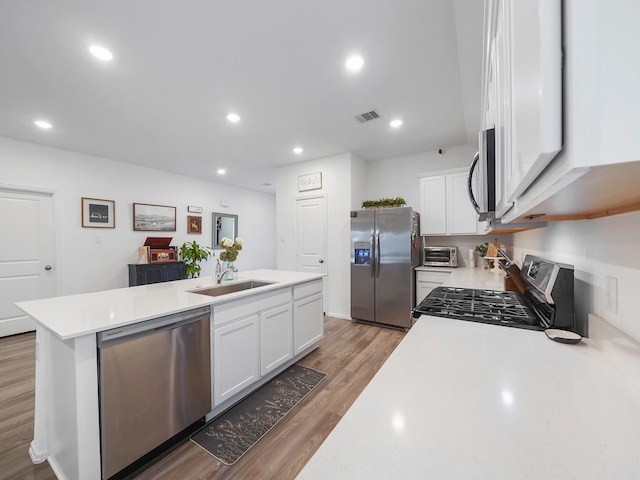 kitchen featuring white cabinets, appliances with stainless steel finishes, sink, dark hardwood / wood-style floors, and a kitchen island with sink