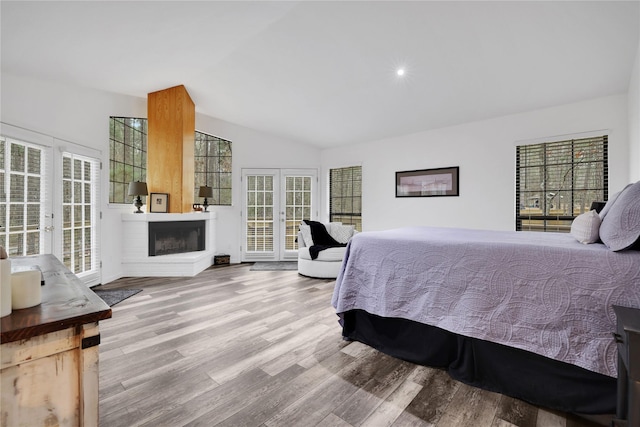 bedroom with vaulted ceiling, access to outside, french doors, multiple windows, and light hardwood / wood-style floors