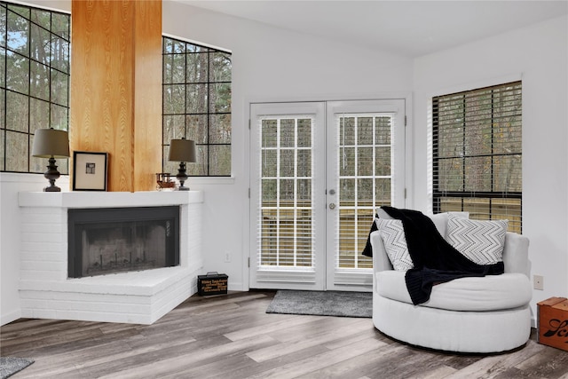 living area with wood-type flooring, a healthy amount of sunlight, french doors, and a fireplace