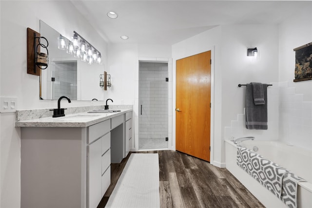 bathroom featuring hardwood / wood-style flooring, vanity, and plus walk in shower