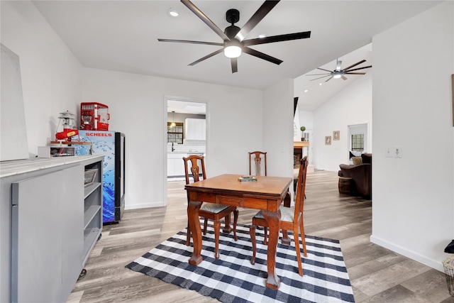 dining room with ceiling fan, lofted ceiling, and light wood-type flooring