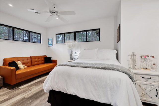 bedroom with ceiling fan, multiple windows, and light wood-type flooring