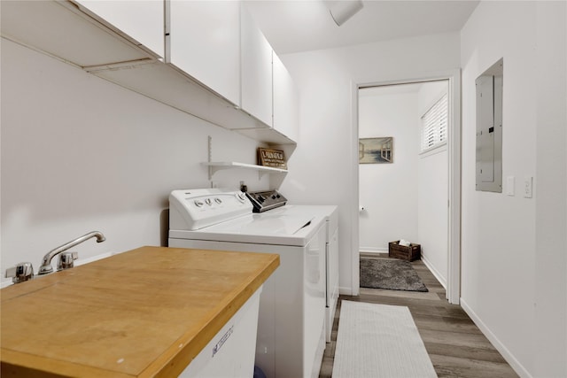 laundry room featuring cabinets, wood-type flooring, electric panel, and separate washer and dryer